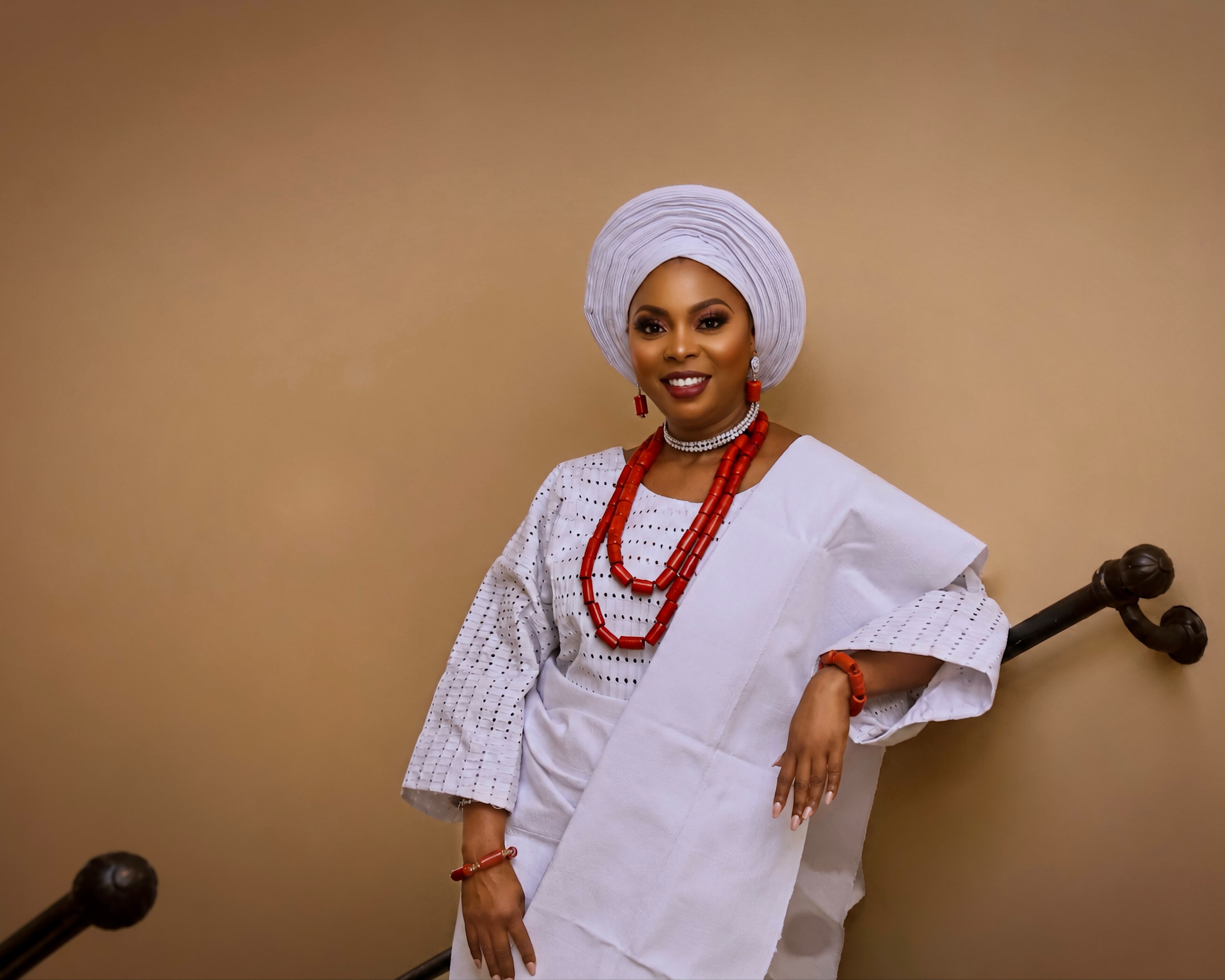 Hands tying an elaborate gold and purple gele headwrap
