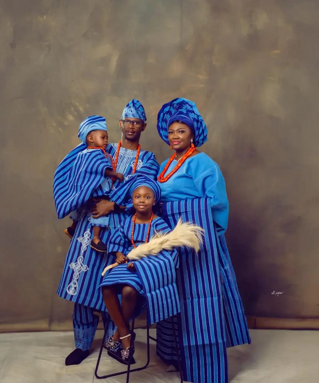 Hands tying an elaborate gold and purple gele headwrap