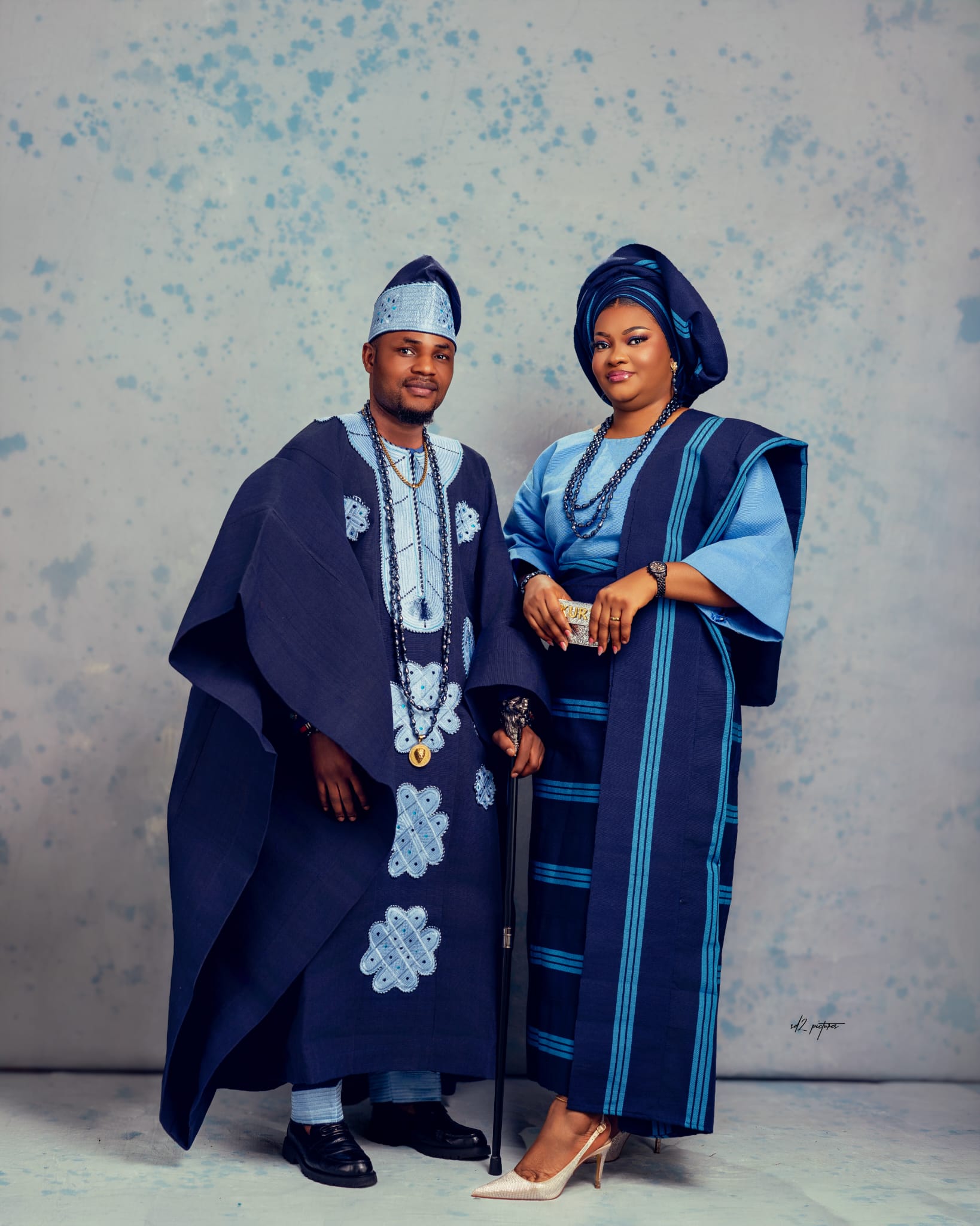 Couple in purple and gold Aso Oke attire with coral beads