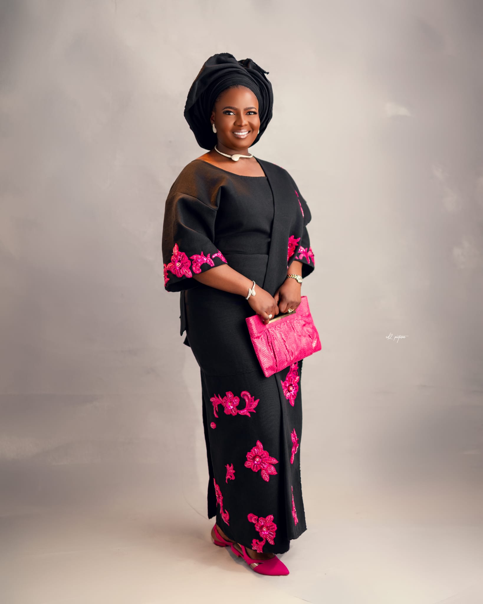 Woman in teal and gold Aso Oke with ornate gele headwrap
