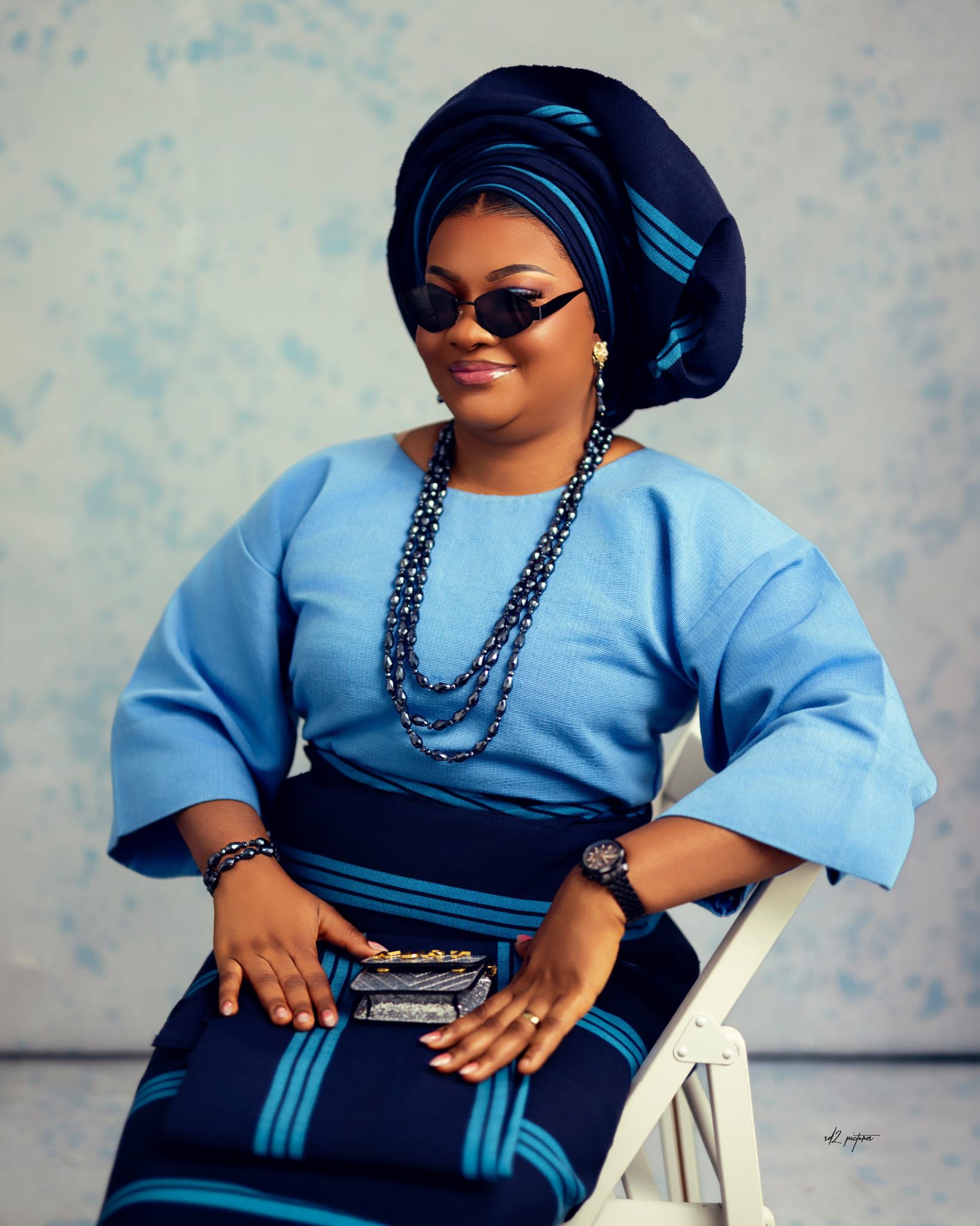 Woman in teal and gold Aso Oke with gele headwrap